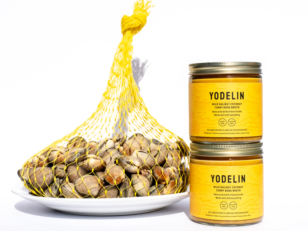 5 pounds of manila clams in a yellow clam bag next to 2 jars of Yodelin wild halibut coconut curry bone broth