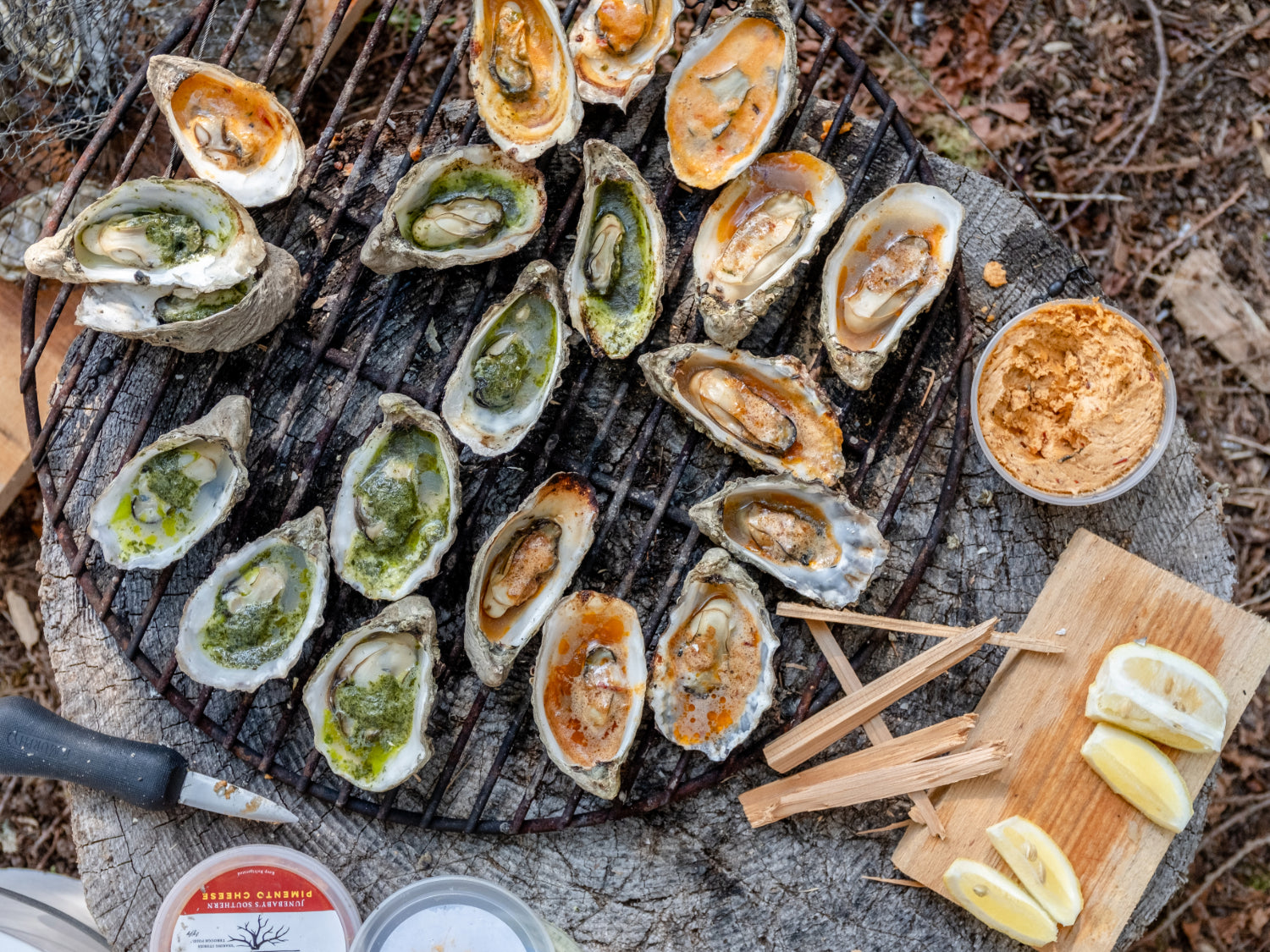 a top down view of grilled small beach grown oysters on the half shell topped with various butters house made by Hama Hama Oyster Company
